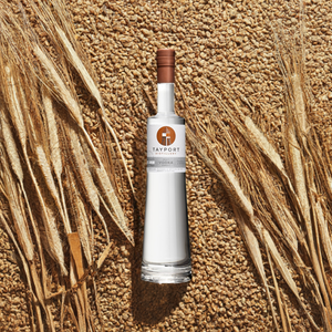 A bottle of vodka elegantly placed atop a bed of golden wheat